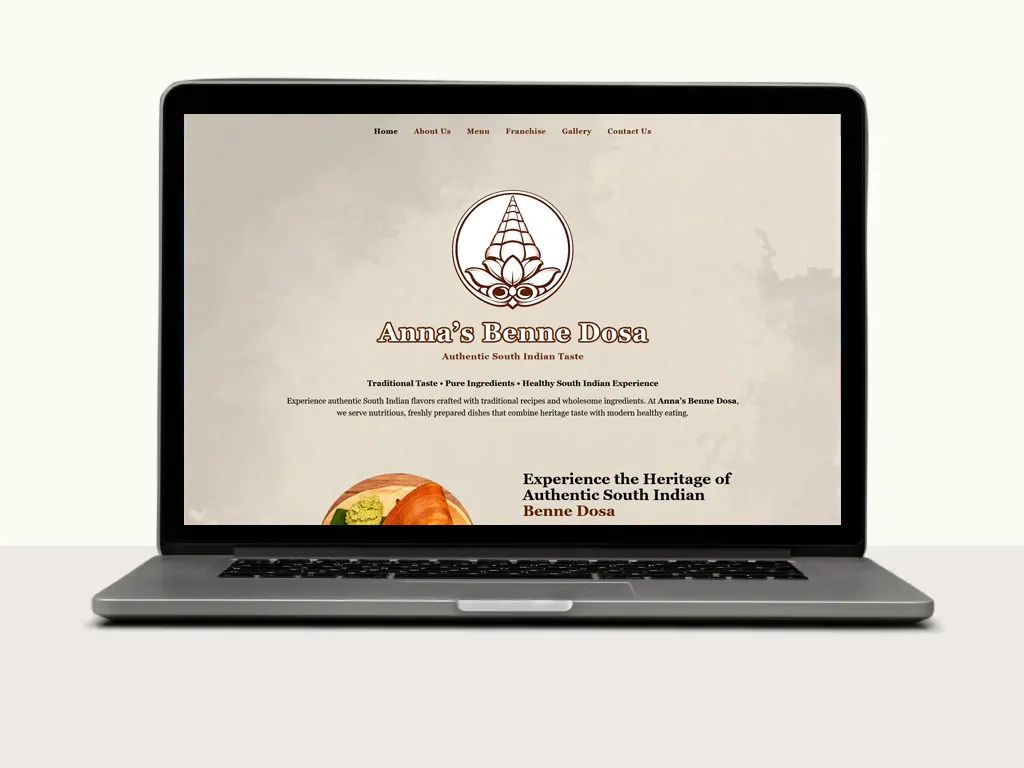 A laptop displays the homepage of Annas Benne Dosa, featuring South Indian dishes, menus, and a welcoming design.